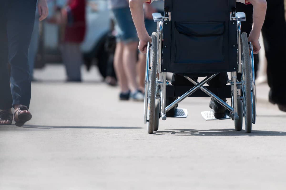 A man with disability propelling his wheelchair along a street.