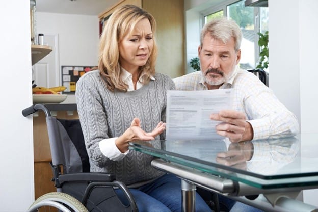 A man and woman in a wheelchair looking at a document asking Will an Inheritance Affect My SSDI?