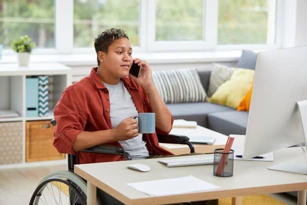 A woman in a wheelchair talking on the phone at home.