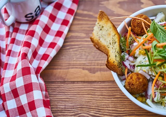 A bowl of food from food stamps on a table with a checkered tablecloth.